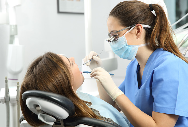 A dental hygienist assisting a patient during a dental appointment.