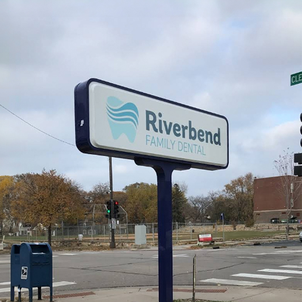 The image shows a sign for Riverbend Family Dental, indicating that it s a dental clinic located at the intersection of two streets.