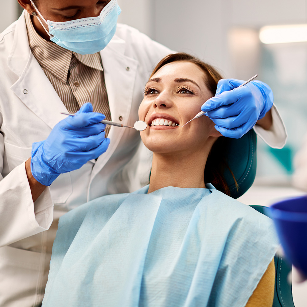 A dental hygienist is performing a teeth cleaning procedure on a patient in a dental office setting.